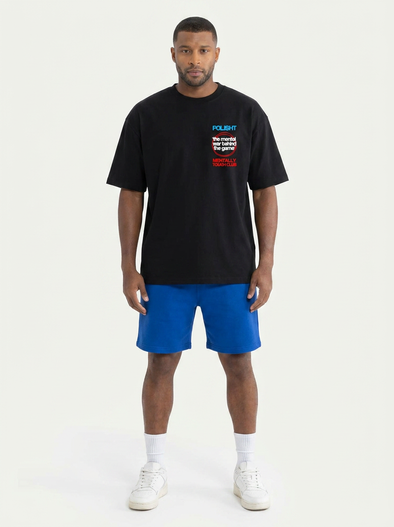 Man wearing a black t-shirt with text and blue shorts on a white background